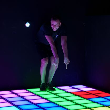 Junger Mann deutet auf einen LED Fliesen Boden, Entertainment Center Attraktion