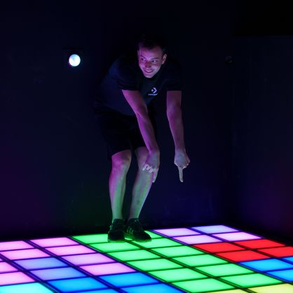 Young man points to an LED tile floor, entertainment center attraction